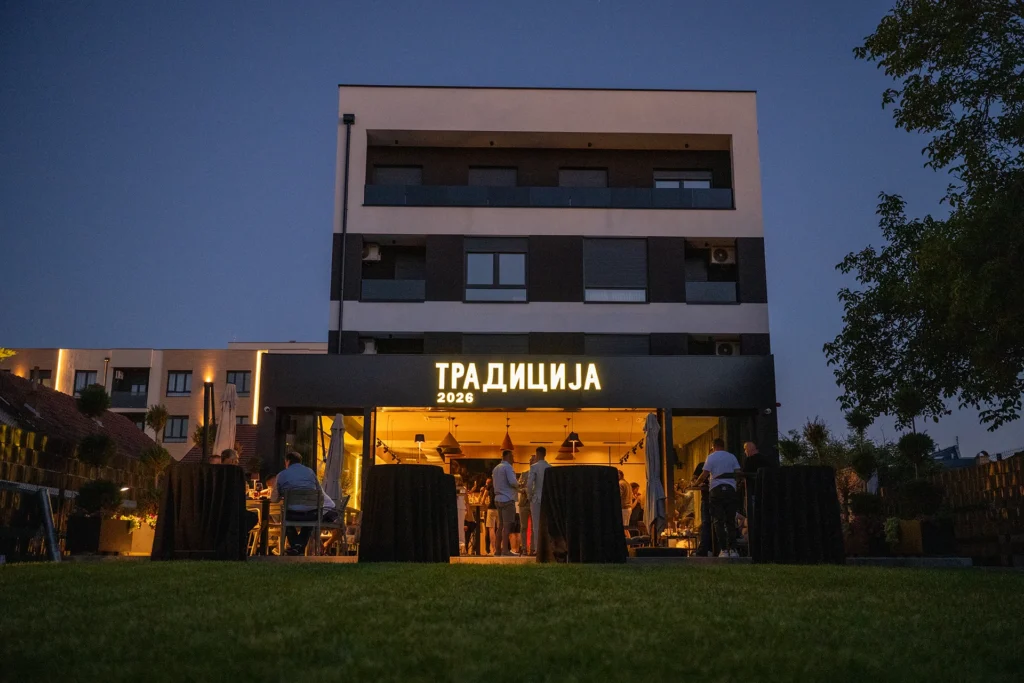 Restoran Tradicija uveče: osvetljen natpis, otvorena bašta i gosti za stolovima